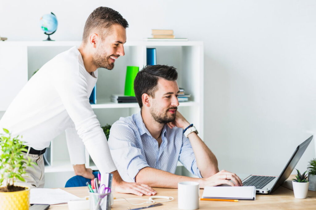 Two colleagues collaborating at a desk with a laptop computer
