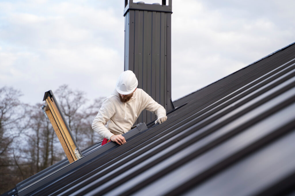 Roofer inspecting modern metal roof for maintenance work