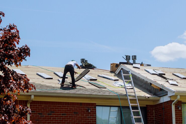 Worker installing new roof shingles on a residential house