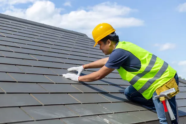 Construction worker inspecting roof tiles in safety gear